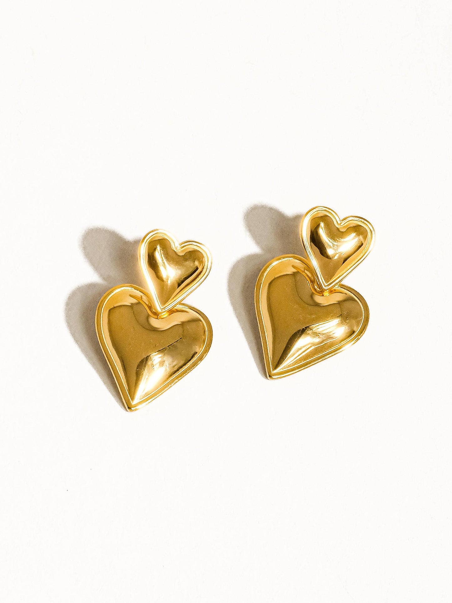 Gold heart-shaped earrings on a white background