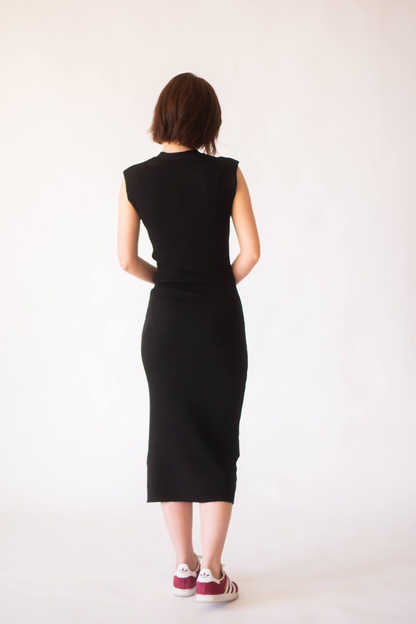 Back of woman in knit black midi dress with cap sleeve.