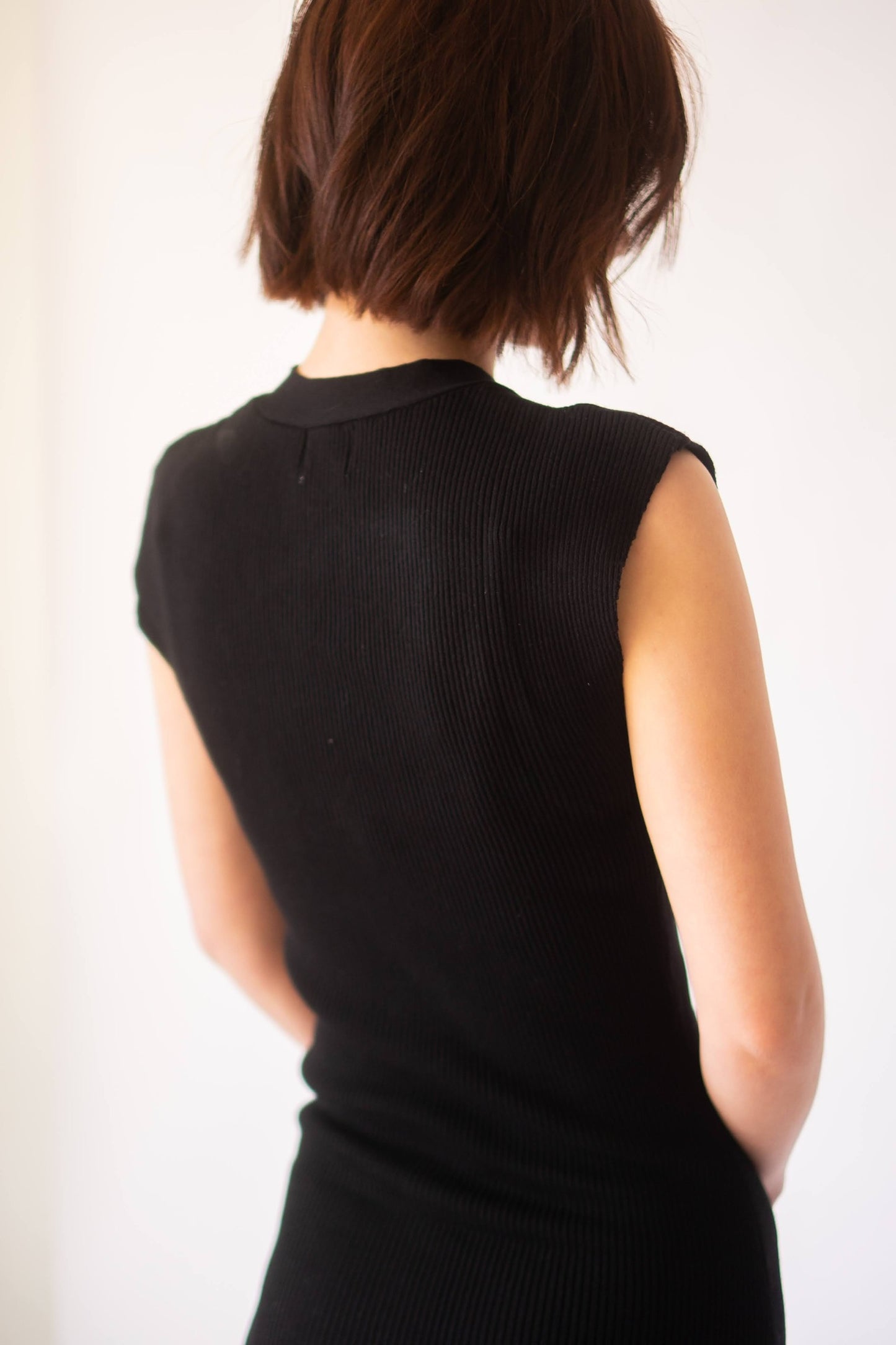 Close up of the back of the knit black dress with cap sleeves.