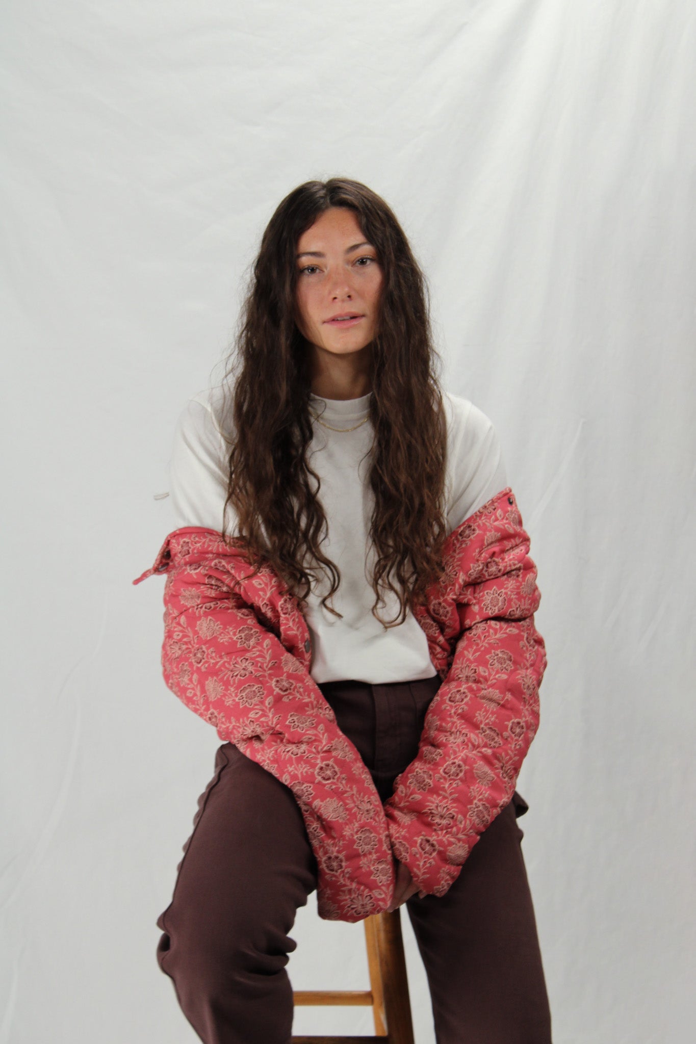 Woman wearing a red patterned jacket over a white t-shirt on a plain background