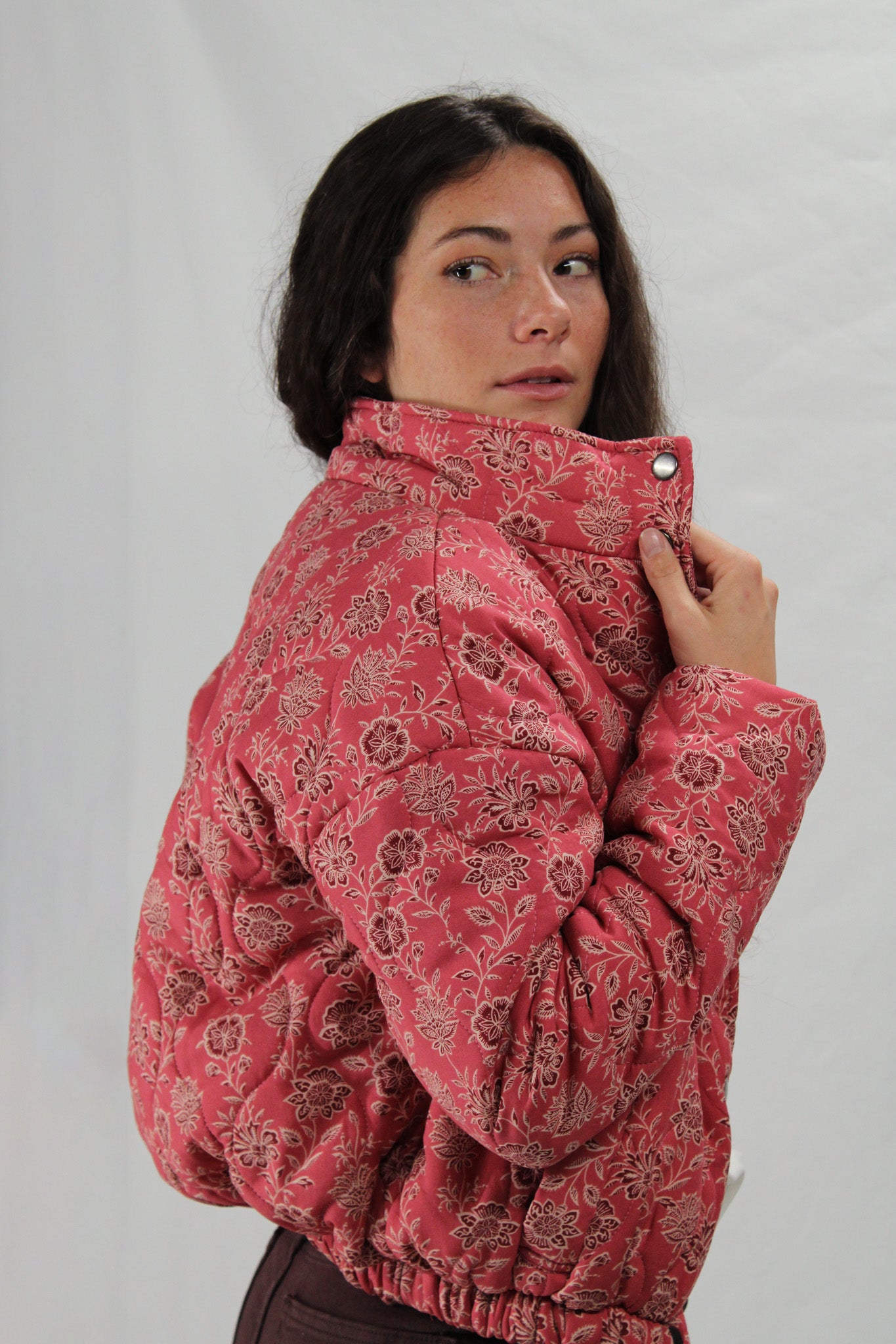 Woman wearing a pink floral-patterned jacket against a plain background