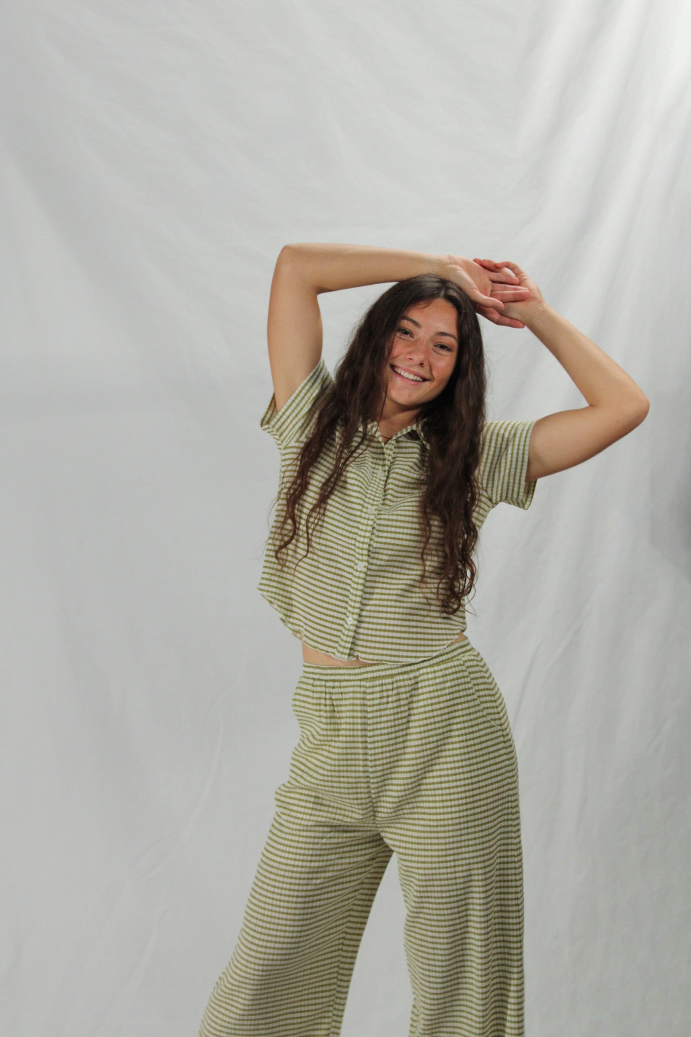 Woman wearing a green striped outfit against a plain background