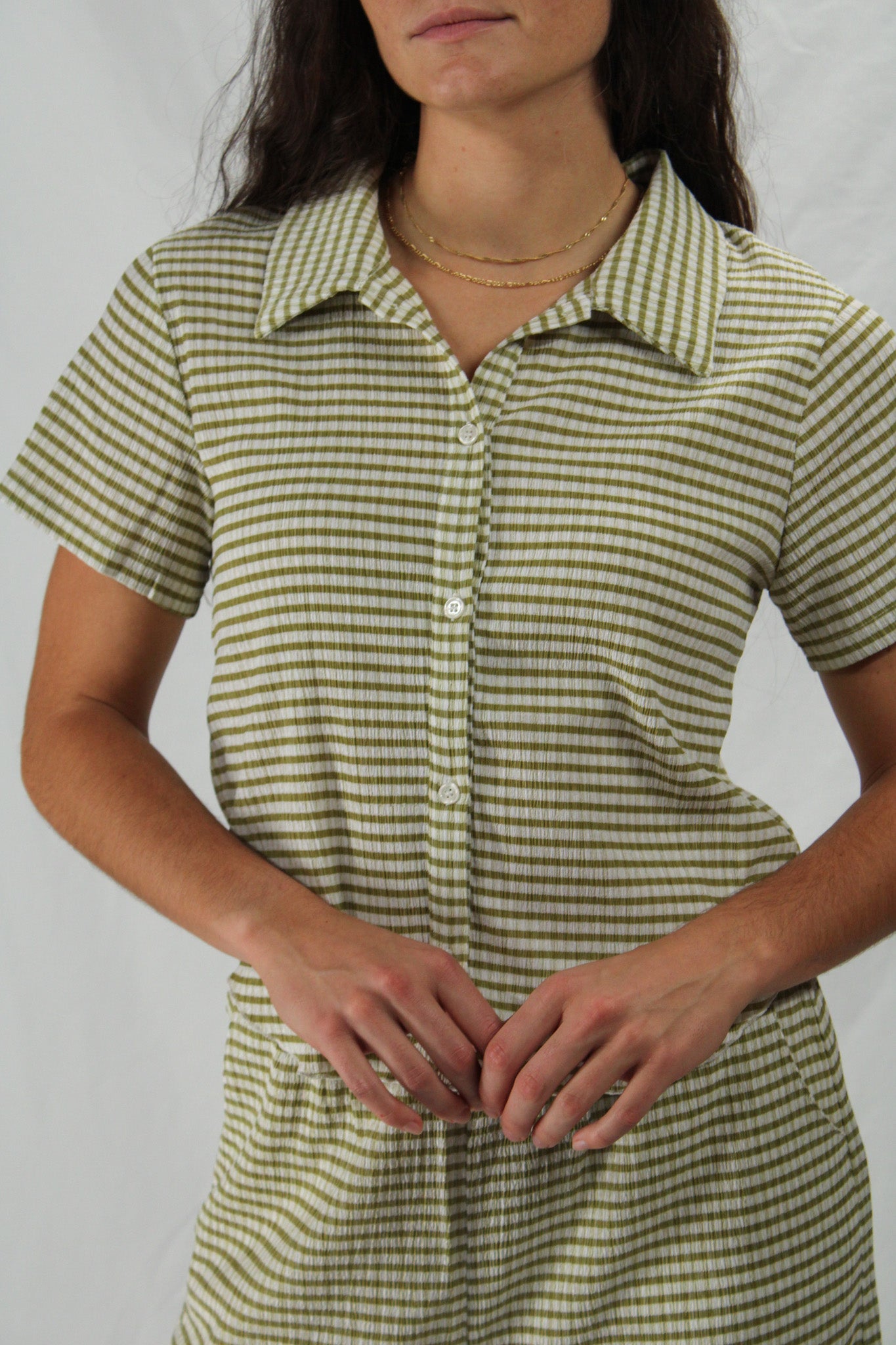 Woman wearing a green and white striped loungewear se against a plain background