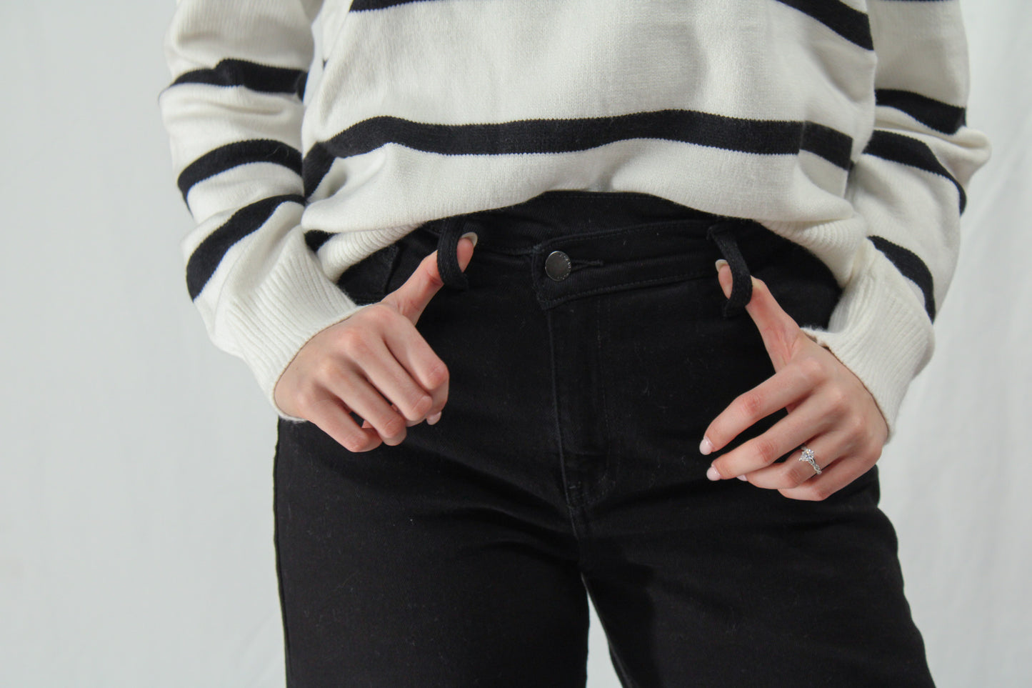 Woman holding belt loops of wide leg black crossover jeans