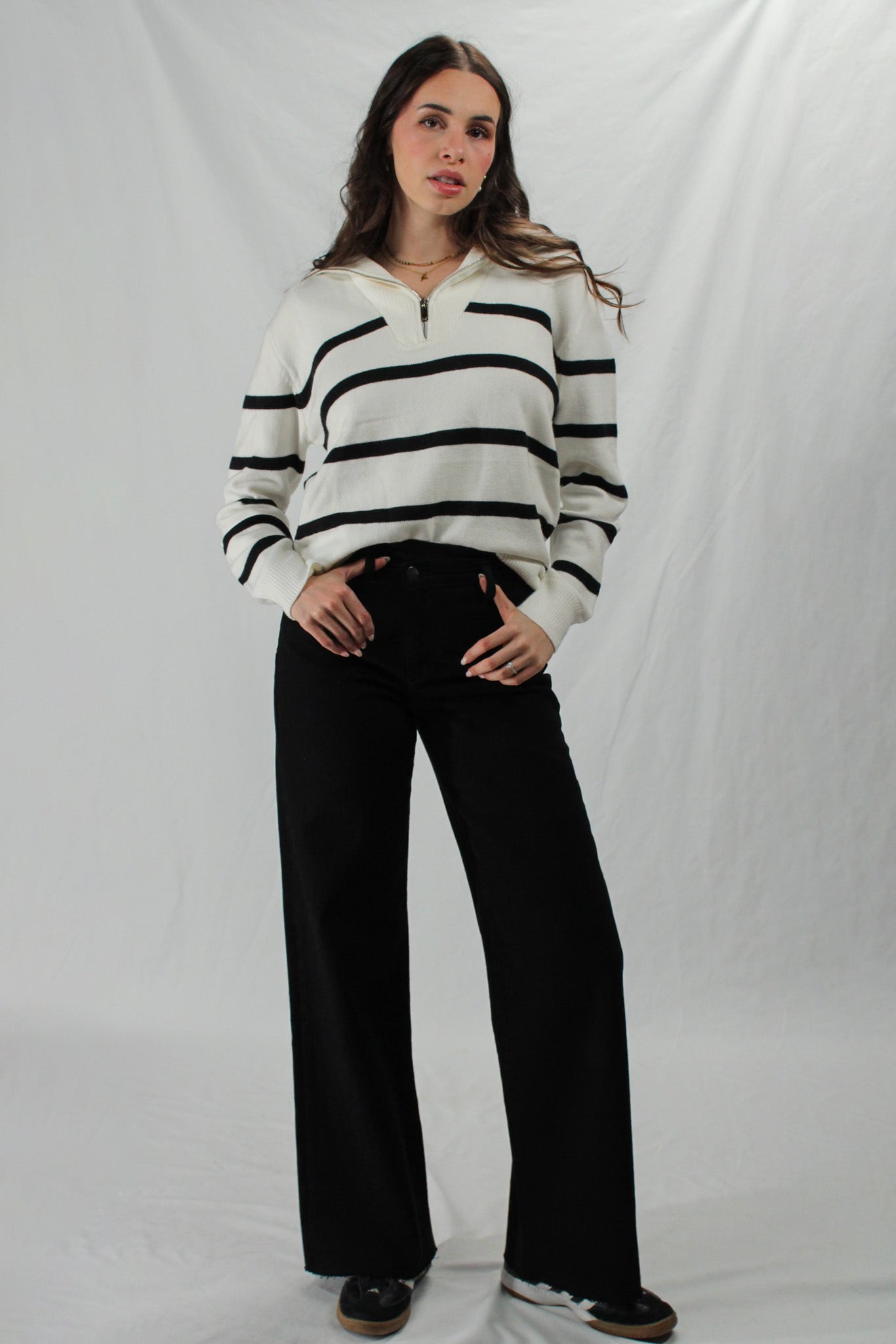 Woman wears wide leg black jeans and black and white striped sweater