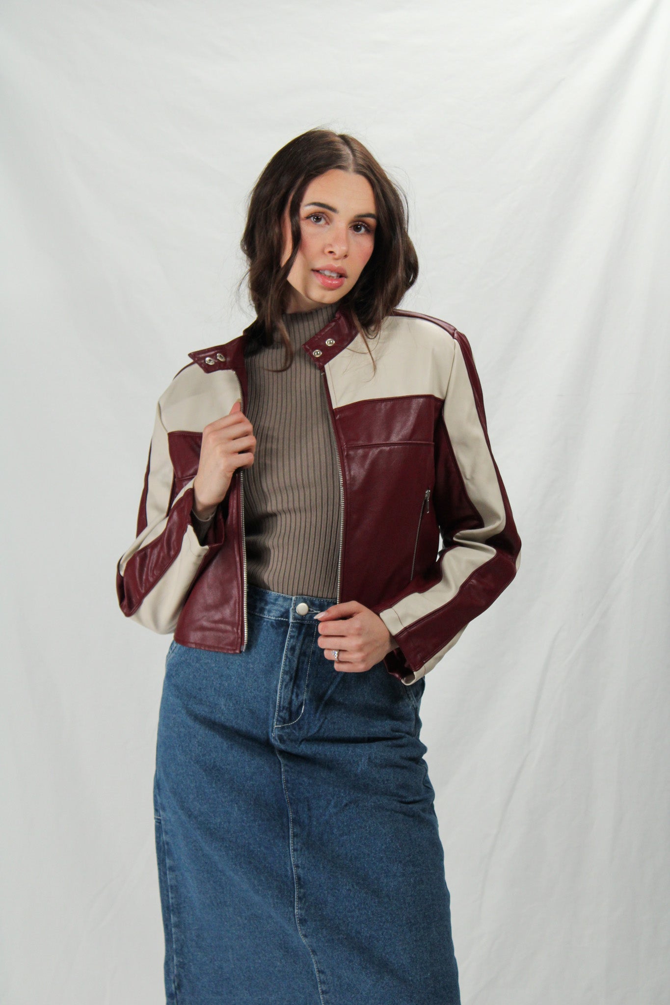 Woman wearing a two-tone jacket with maroon and beige panels on a white background