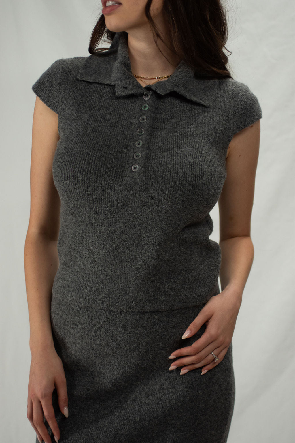 Grey knit quarter button sweater polo with cap sleeve and iridescent buttons.