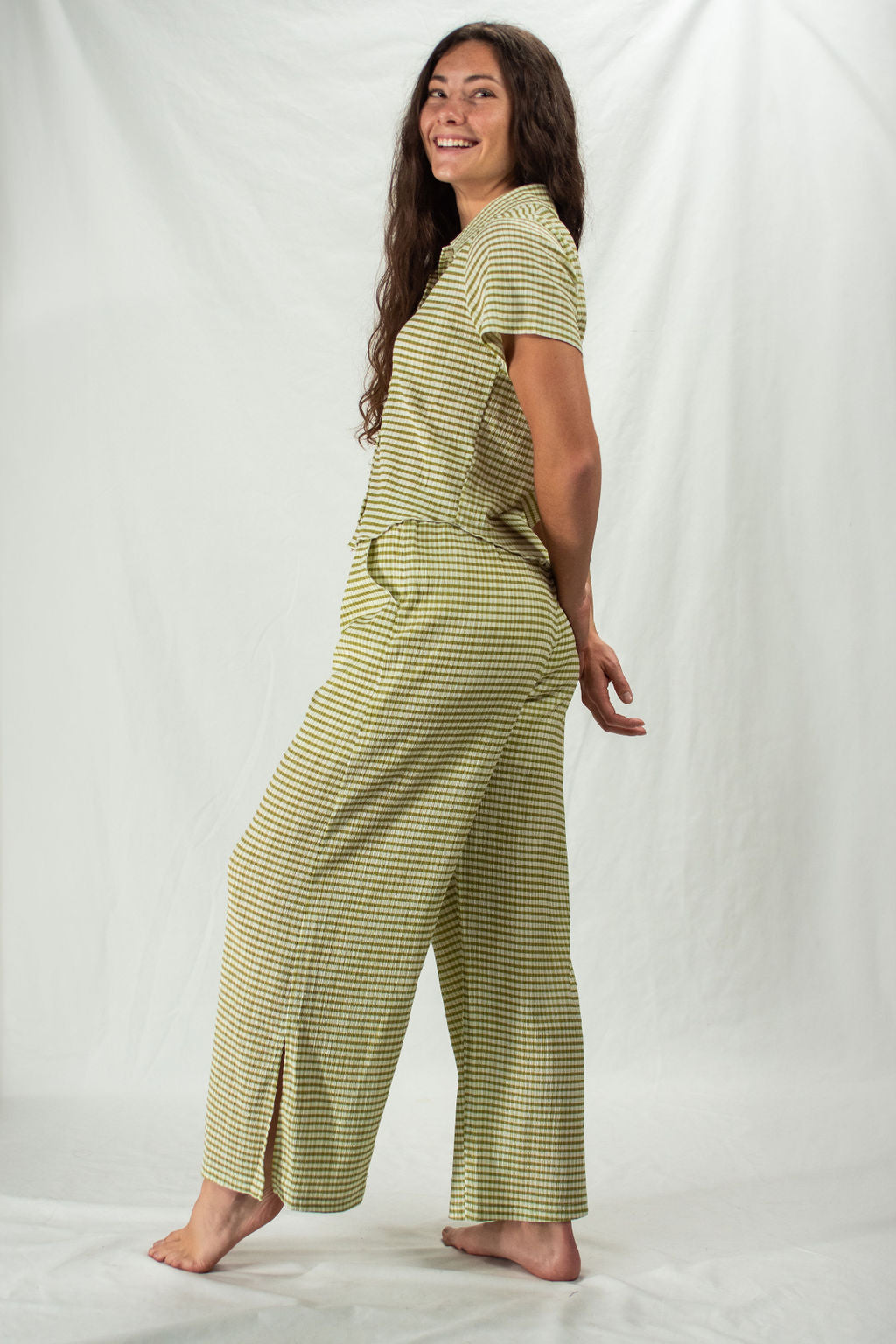Woman wears wide leg green and white striped pants with split hem and pockets