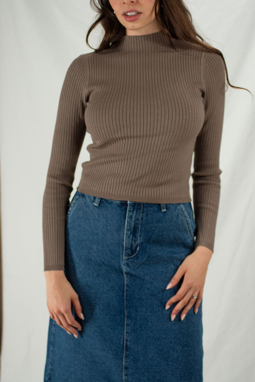 Woman wears a brown ribbed mock neck fitted sweater with cropped fit