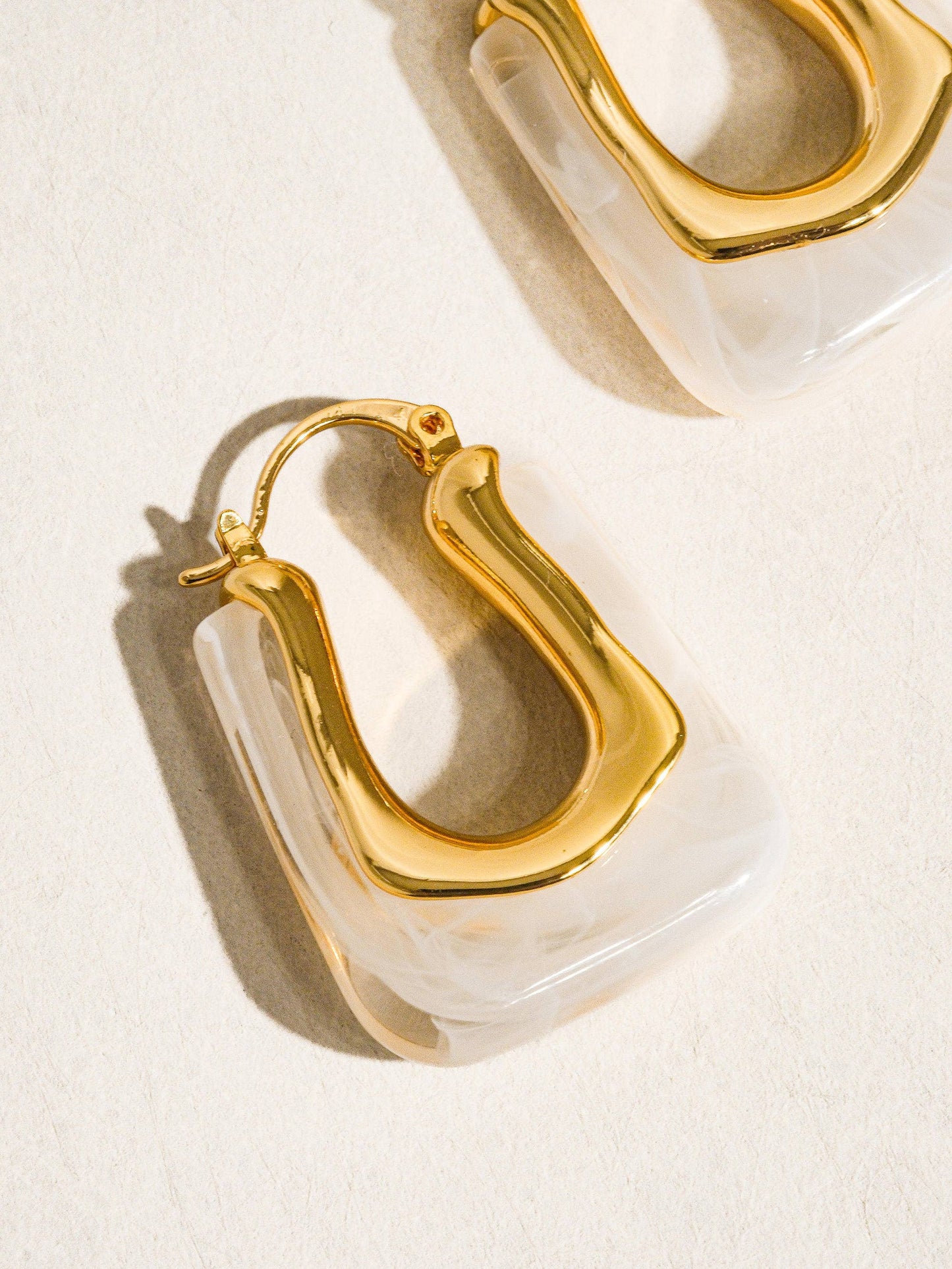 Gold hoop earrings on a light beige background