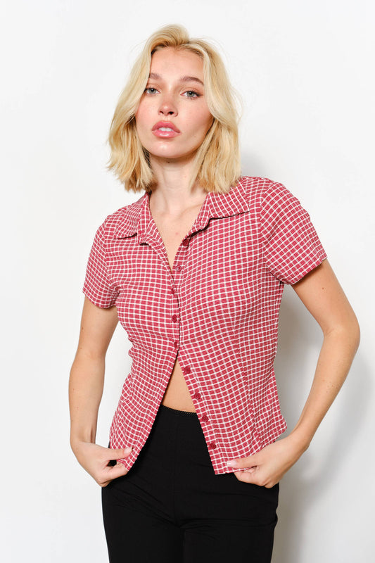 Woman wearing a red checkered short sleeve shirt against a white background