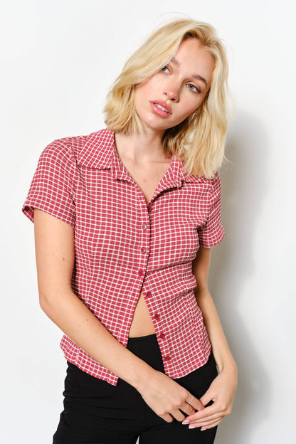 Woman wearing a red and white checkered shirt against a plain background