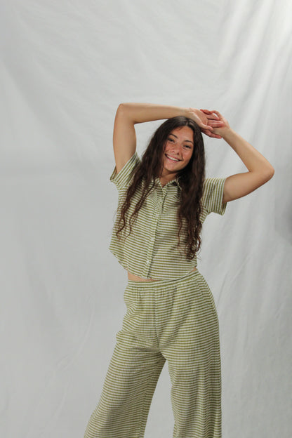Woman wearing a green striped outfit against a plain background