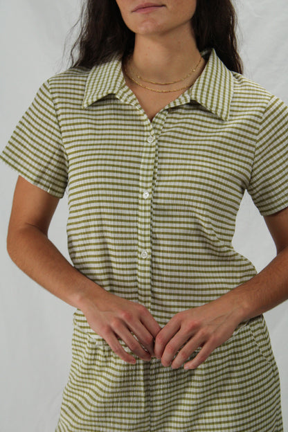 Woman wearing a green and white striped loungewear se against a plain background