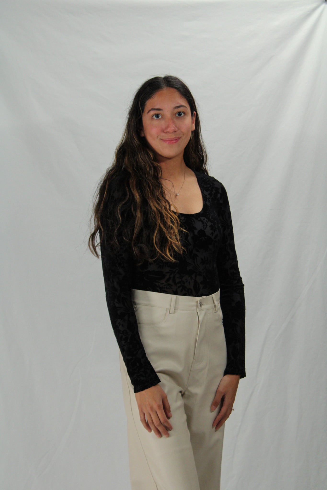 Woman wearing black long sleeve bodysuit with velvet floral detailing and scoop neck.