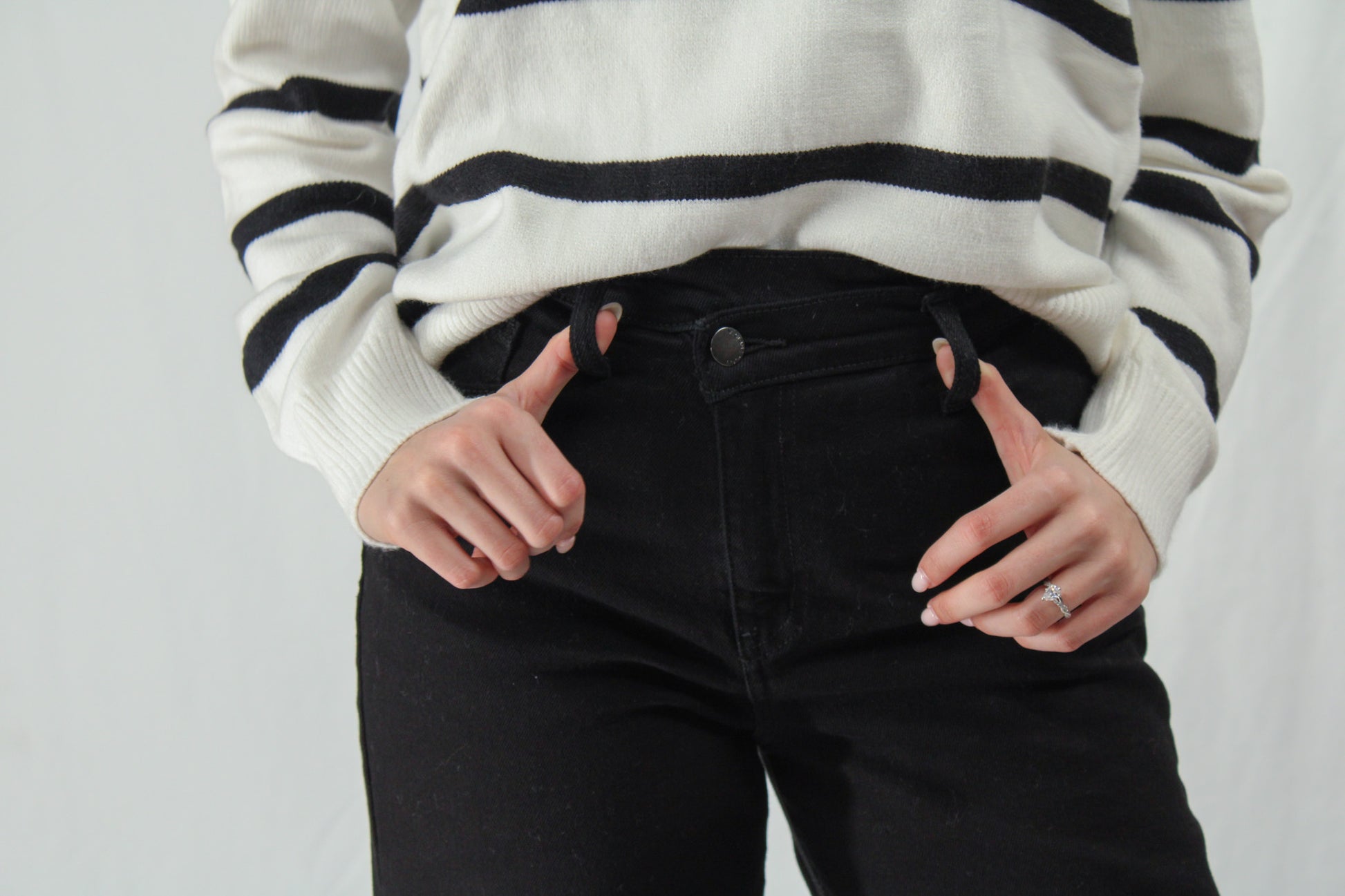 Woman holding belt loops of wide leg black crossover jeans