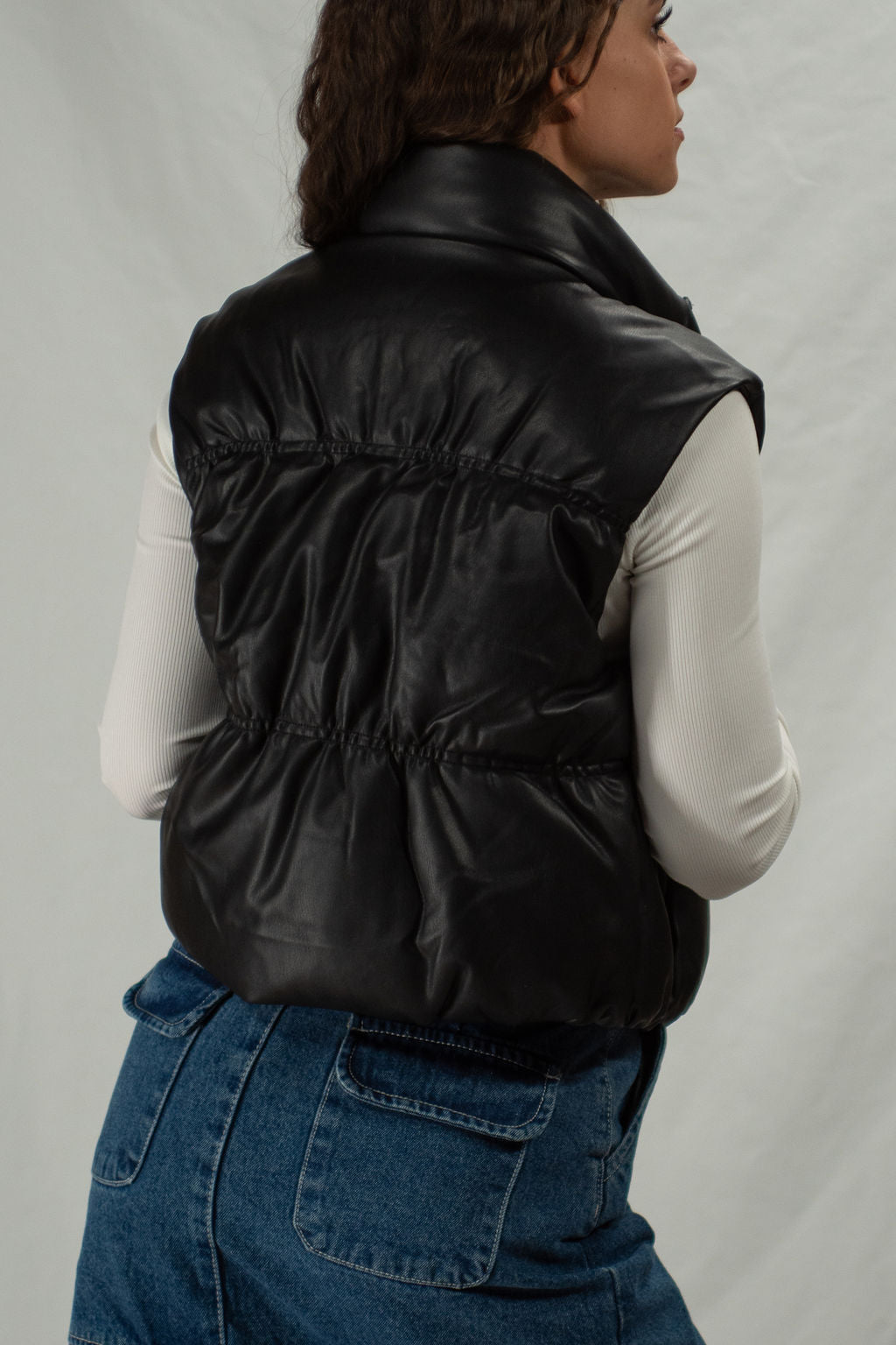 Back of black zip-up vegan leather puffer vest