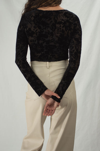 Back of black bodysuit with floral velvet accents, long sleeves, slightly sheer.
