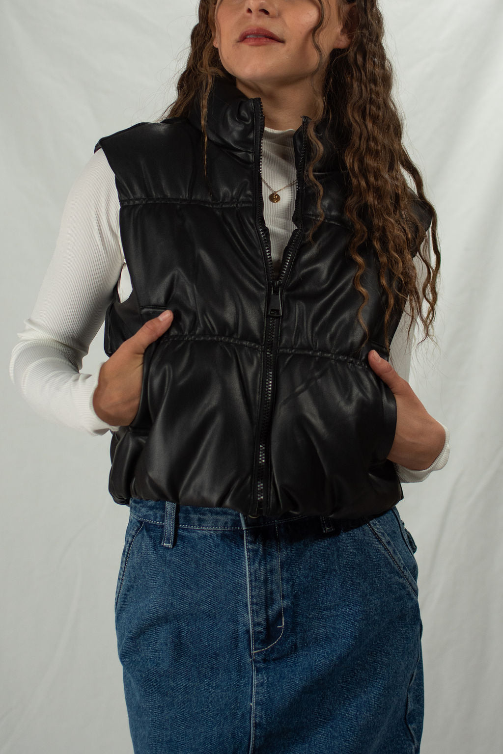 Girl wearing black zip-up vegan leather puffer vest