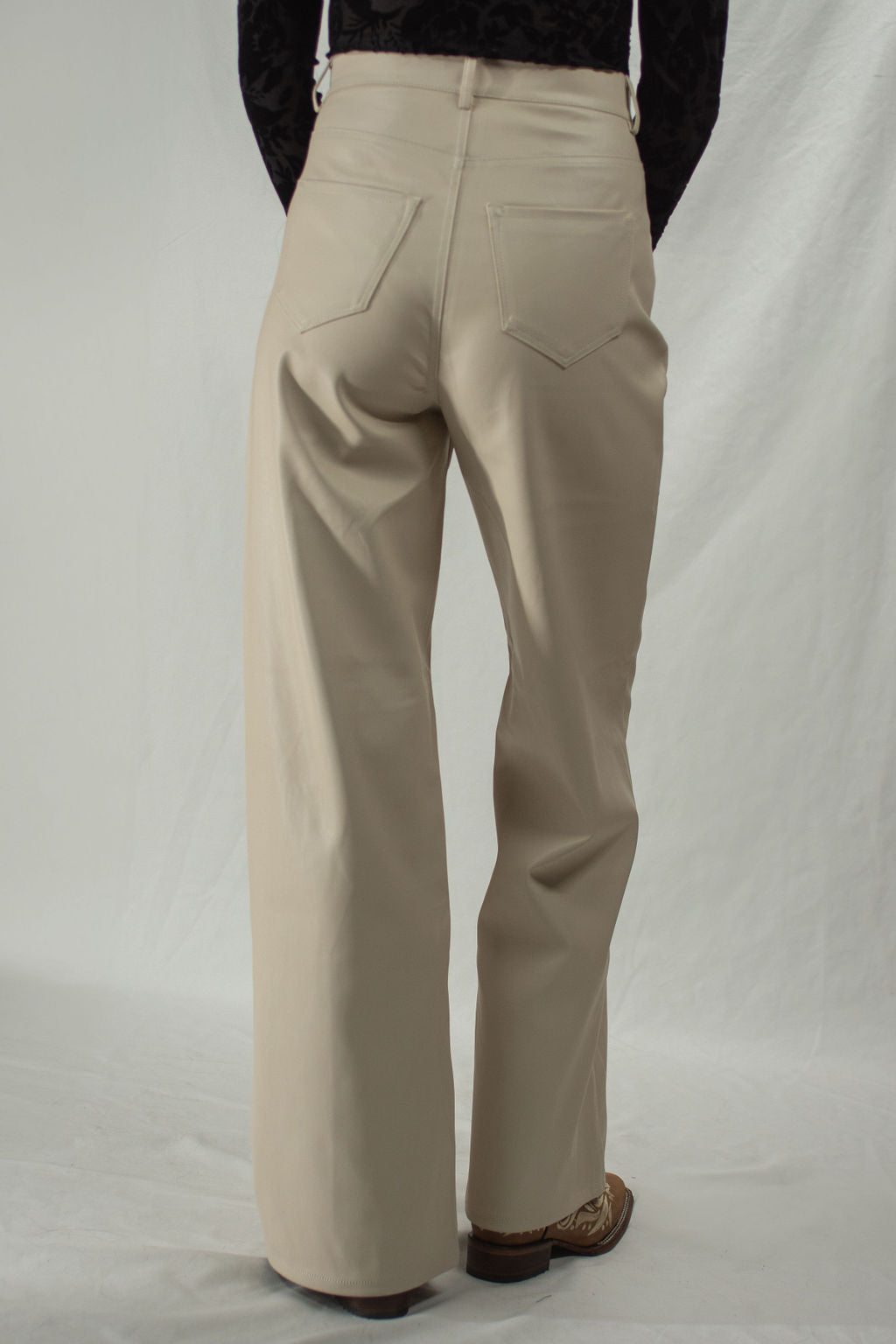 Back of faux leather cream pants in a wide leg cut