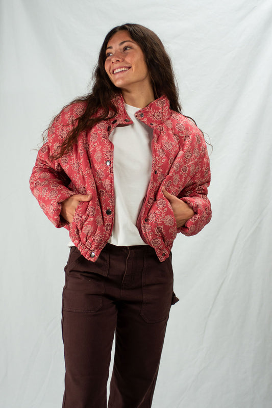 Woman wearing a red patterned jacket over a white shirt and brown pants on a white background