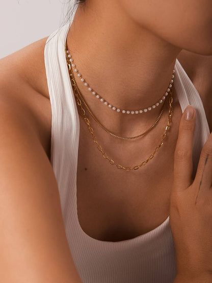 Close-up of a person wearing multiple gold necklaces and a pearl necklace