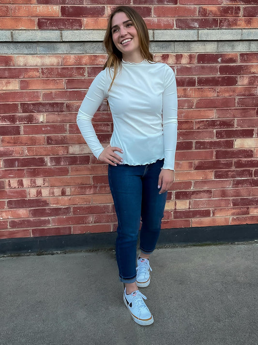 Girl wearing white lettuce hem mock neck and straight leg jeans