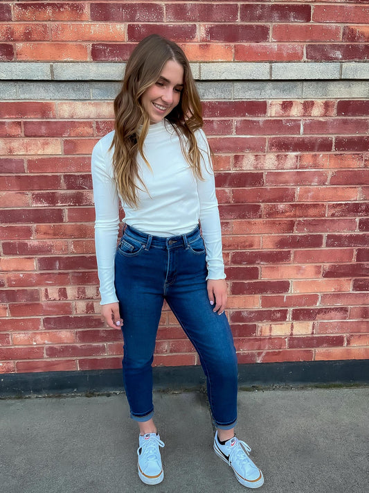 Girl wearing white lettuce hem mock neck and straight leg jeans