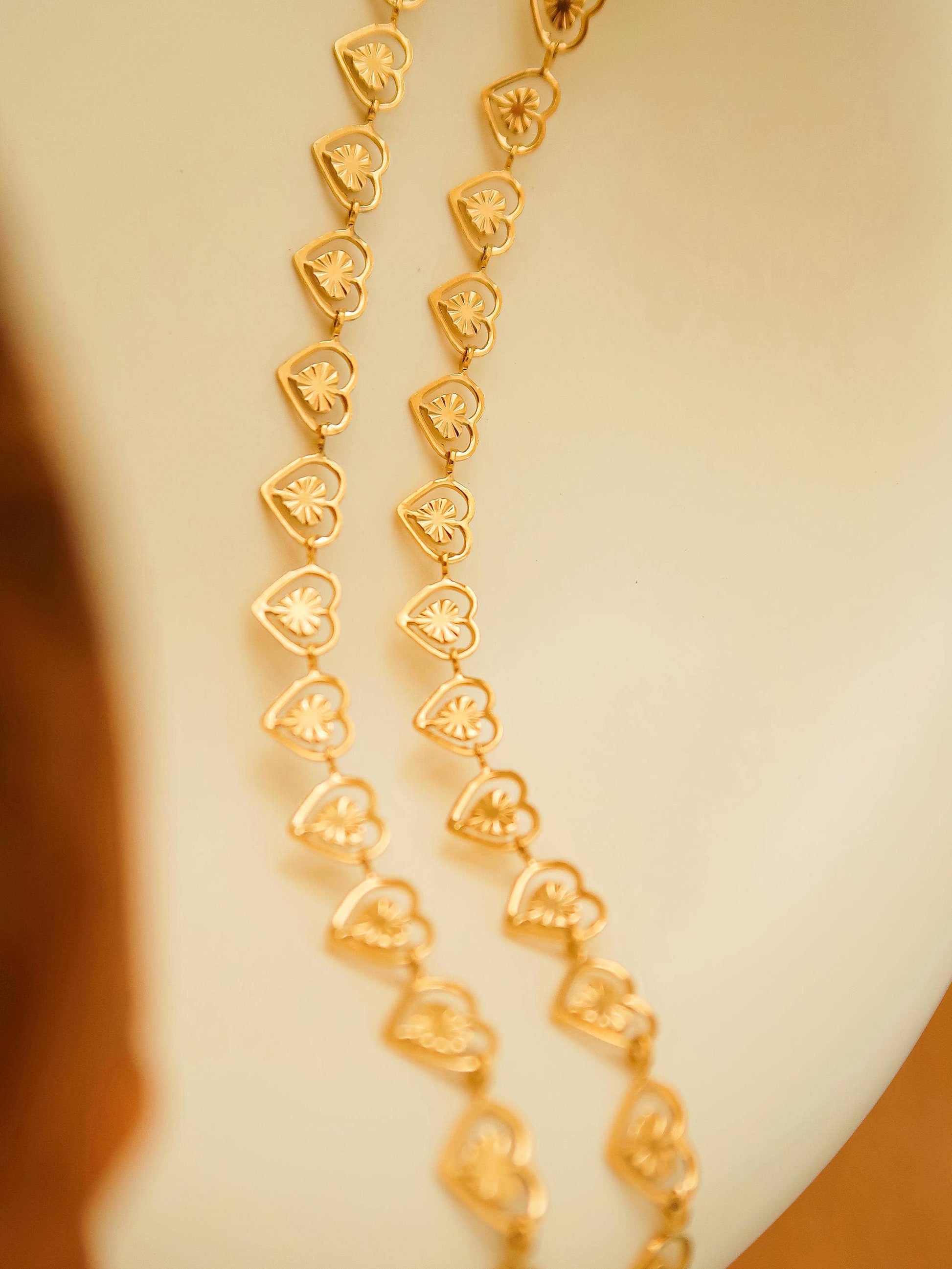 Gold necklace with heart-shaped links on a neutral background
