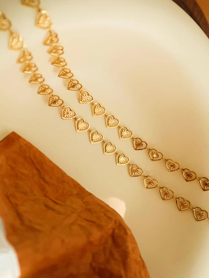 Gold necklace with heart patterns on a white surface