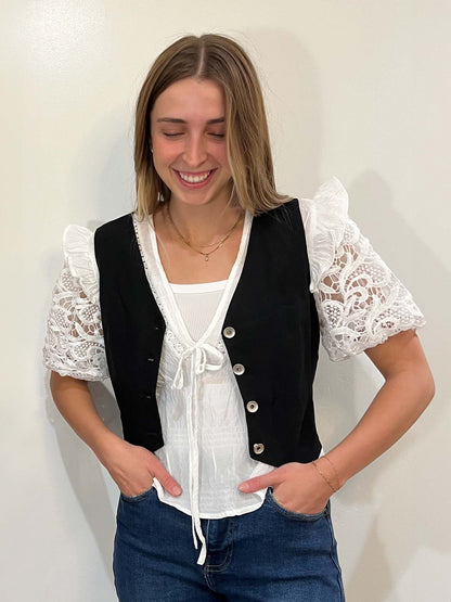 Black vest over white lace puff sleeve blouse